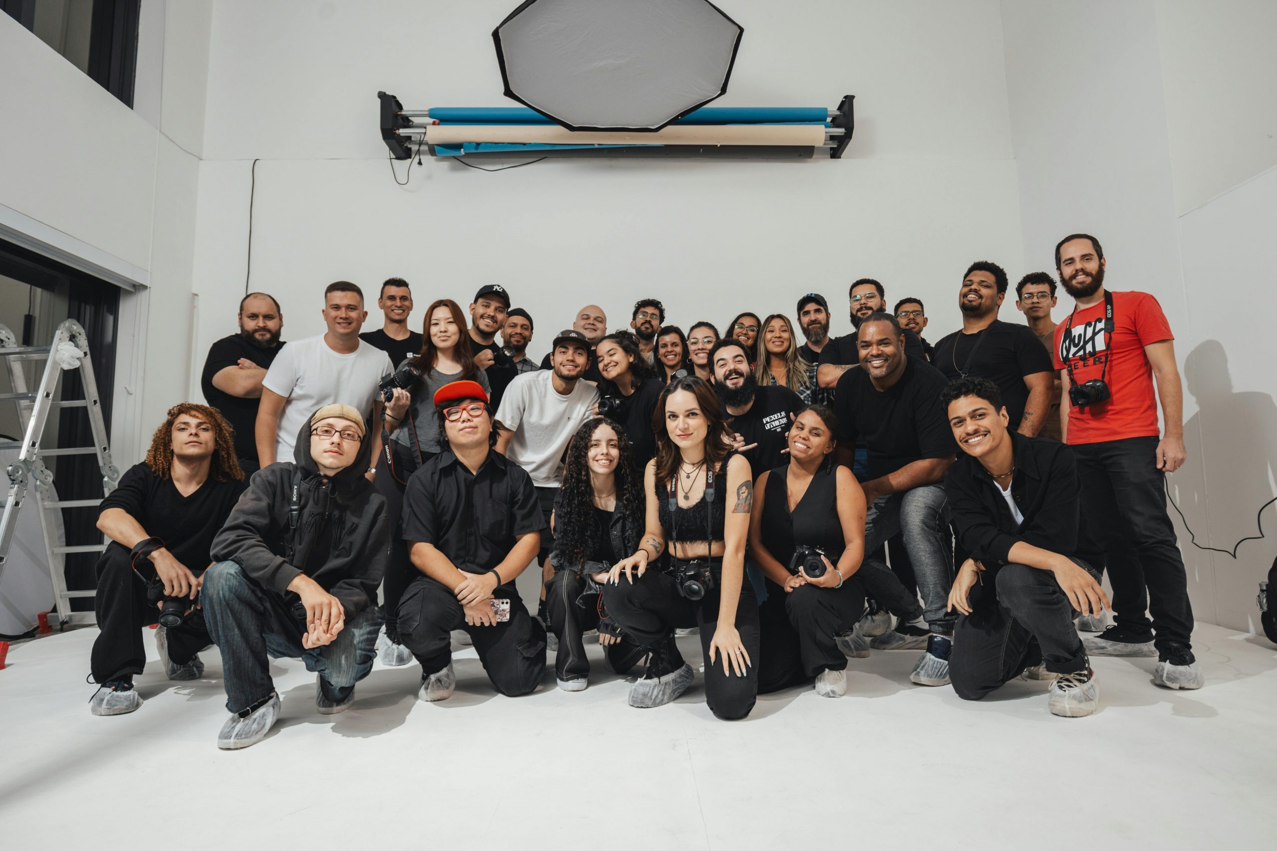 A large group of photographers gathered in a brightly lit photo studio, showcasing diversity and creativity.